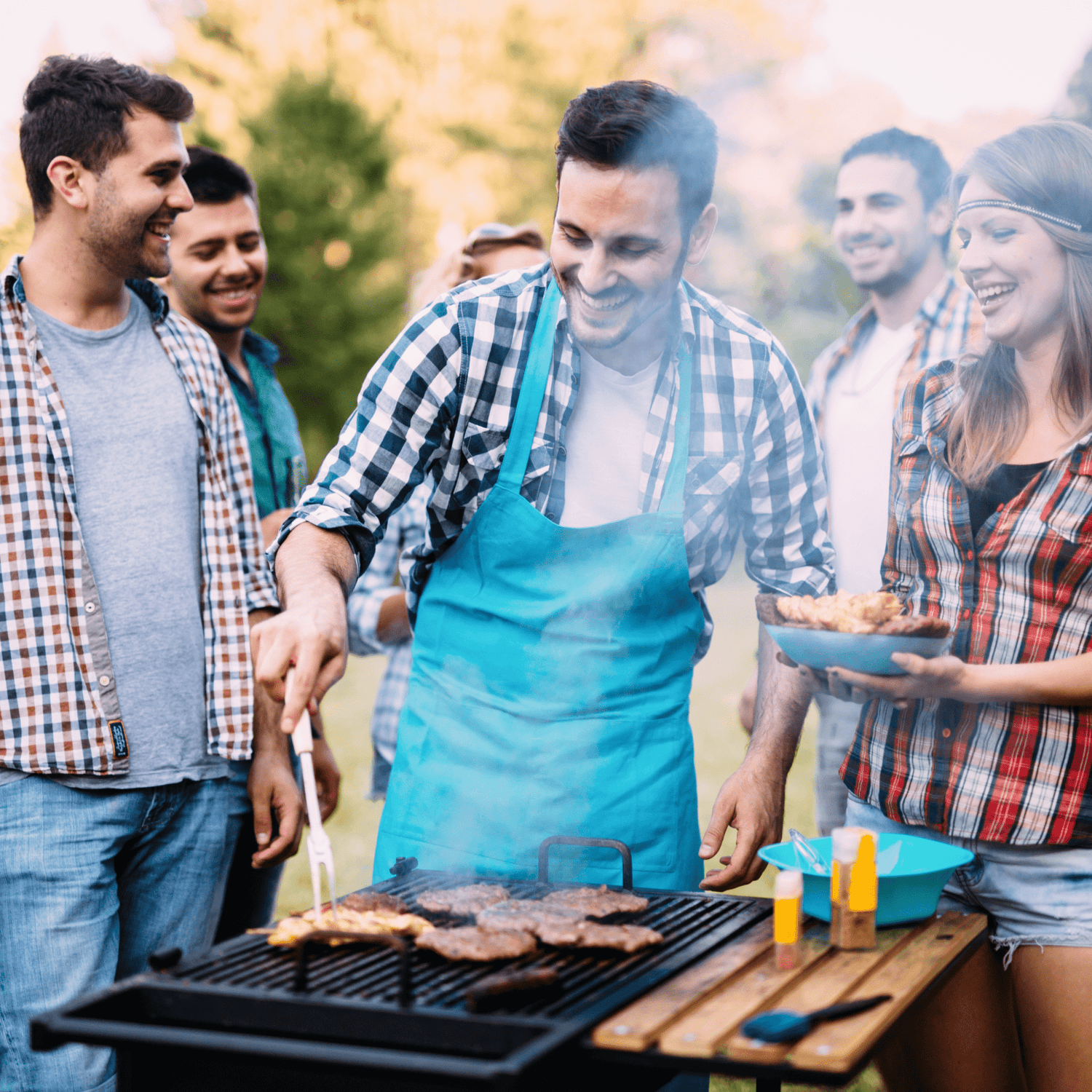 a group of people standing around a barbecue grill